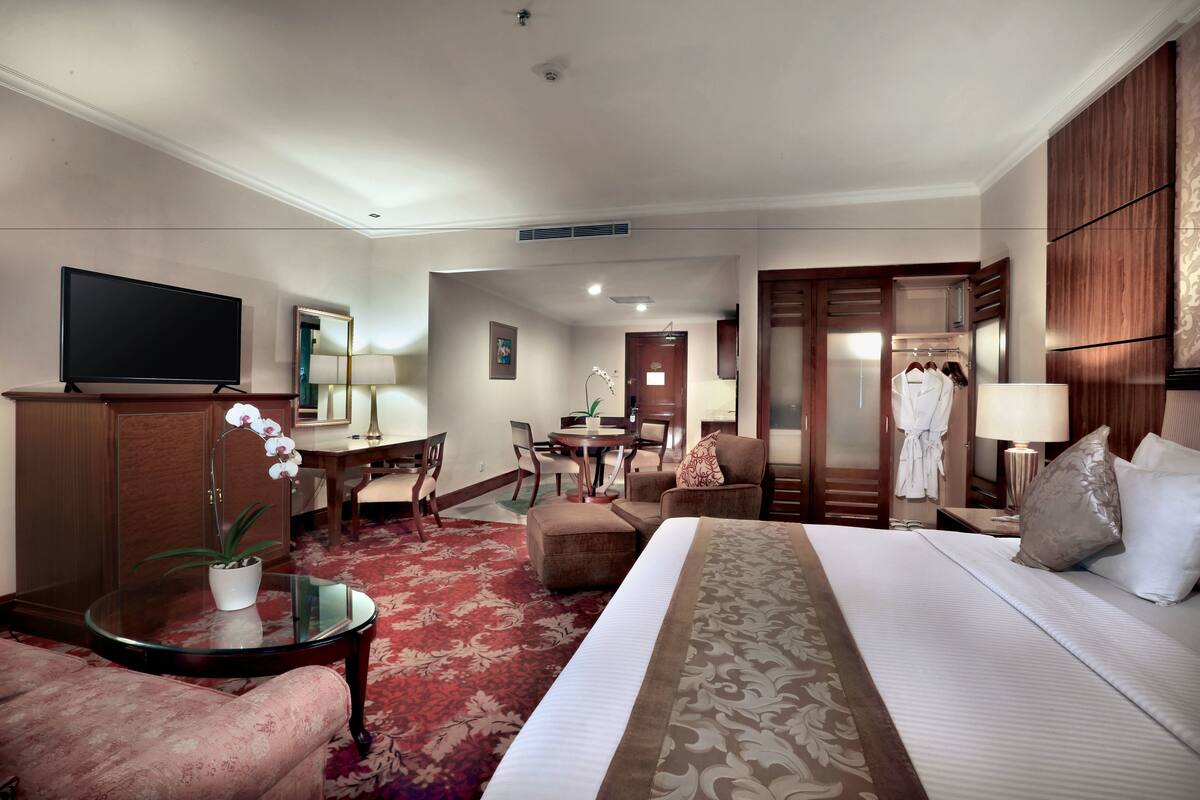 Habitación de hotel con cama, televisión, escritorio, silla, armario y baño.