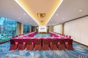 Une salle de conférence avec une longue table, des chaises et un écran affichant le texte « ASTON TROPICANA ».
