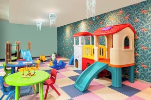 A children's play area with a slide, climbing structures, and a train-themed playhouse. - Aston Tropicana Hotel Bandung (Coblong)