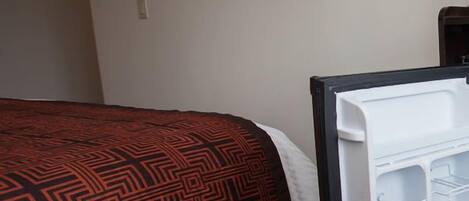 A hotel room with a bed, a TV mounted on the wall, and a white storage unit with multiple compartments.