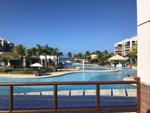 Relax by the resort's large, curved pool surrounded by lush greenery and palm trees.