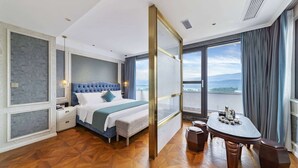 A hotel room with a large bed, a desk, and a view of the city. - Howard Johnson by Wyndham Lake Serenity Hot Springs Xichang (Liangshan Yi)