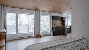 A modern interior with large windows, a wooden ceiling, and a kitchen area.