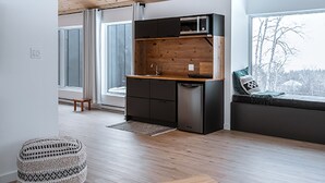 A modern living space with a wooden ceiling, a kitchen area, and large windows.