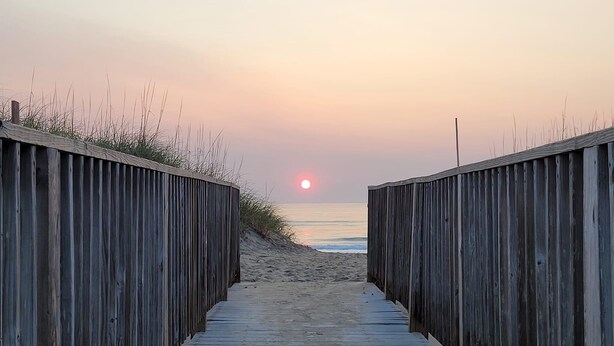 A wooden boardwalk leading to a beach with a sunset in the background. - Bright and sunny family friendly cottage, 2 minutes to beach, Sound view sunsets (Kill Devil Hills)