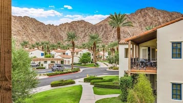 A residential area with houses, a paved road, and a mountain backdrop.