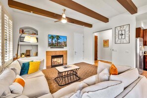 A living room with a fireplace, a ceiling fan, and a television.