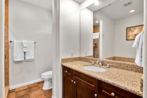 Ein Badezimmer mit Toilette, Waschbecken mit Granitplatte und großem Spiegel.