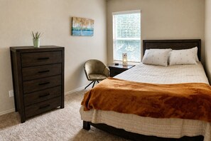 A bedroom with a bed, a dresser, a chair, a window with blinds, and a painting on the wall. - King Bed Yard/Grill-Long Term Stays Near Fort Hood: Pet Friendly (Copperas Cove)