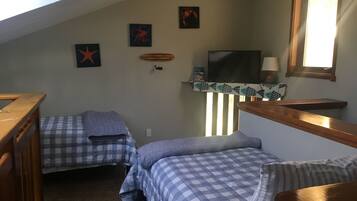 A room with two beds, a TV, and artwork on the walls.