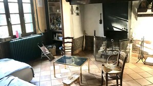 Un salon chaleureux avec une cheminée, une bibliothèque et une fenêtre équipée de stores.