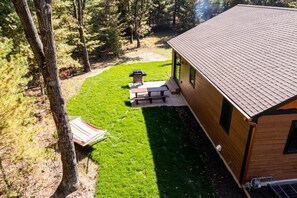 Una cabaña con un patio, una parrilla y una mesa de picnic.