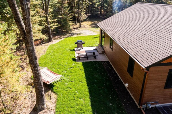 Una cabaña con un patio, una parrilla y una mesa de picnic.