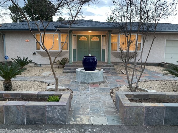 Una casa con una porta verde, un vaso blu grande al centro e un vialetto in pietra che conduce all'ingresso.