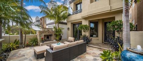 A patio with outdoor furniture, a stone fireplace, and various plants.