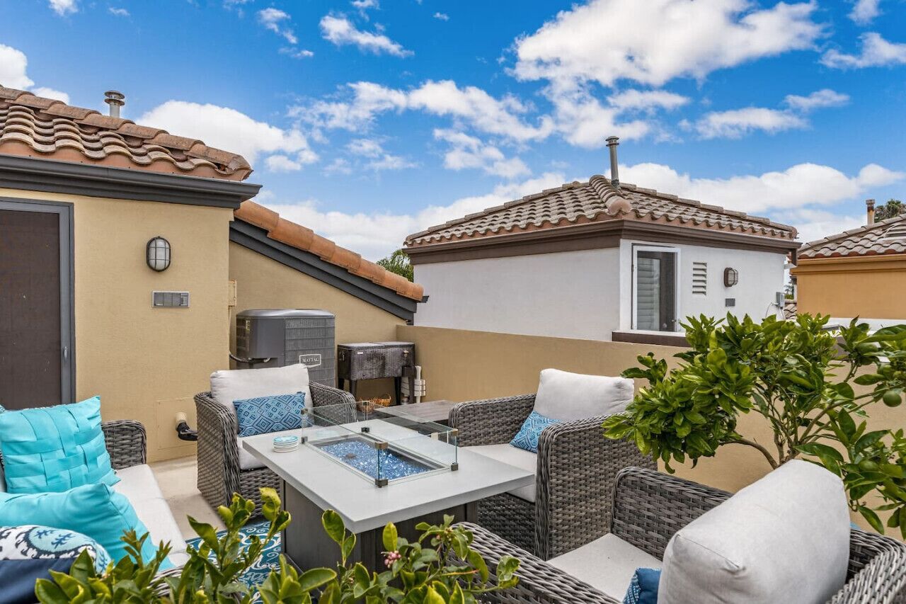 A patio area with wicker furniture, a glass-top table, and a small water feature.