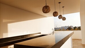 Una cocina moderna con una isla central, luces colgantes y vistas a la ciudad.