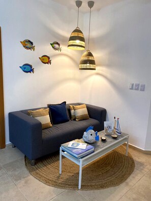 A living room with a sofa, a coffee table, decorative fish wall art, and pendant lights.