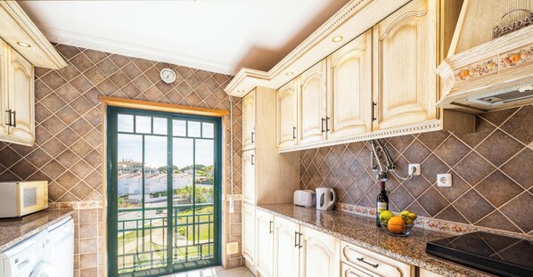 Una cocina con armarios de madera, microondas, tostadora y ventana con vistas al exterior.