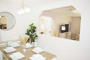 A dining area with a table set for four, a mirror, and a plant.