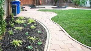 A curved brick pathway leading to a grassy area with a wooden fence in the background. - Remodeled + Fully Equipped + Big Backyard (Turlock)