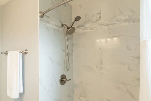 A bathroom with a shower, marble tiles, and a towel rack. - Remodeled + Fully Equipped + Big Backyard (Turlock)