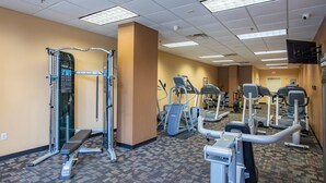 Een sportschool met diverse fitnessapparaten, waaronder loopbanden, elliptische trainers en krachtapparaten.