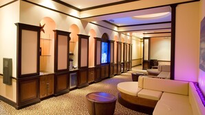Een hotellobby met een receptiebalie, een zithoek en een televisiescherm.