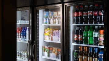 Un refrigerador de bebidas repleto de diferentes opciones de bebidas y aperitivos.
