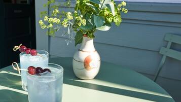 Une table avec deux verres de boissons glacées, des cerises et un vase rempli de fleurs.