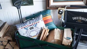 Une valise verte remplie de bois, un coussin aux couleurs vives et un sac noir sur lequel on peut lire : « The Drifthaven at Gearhart ».