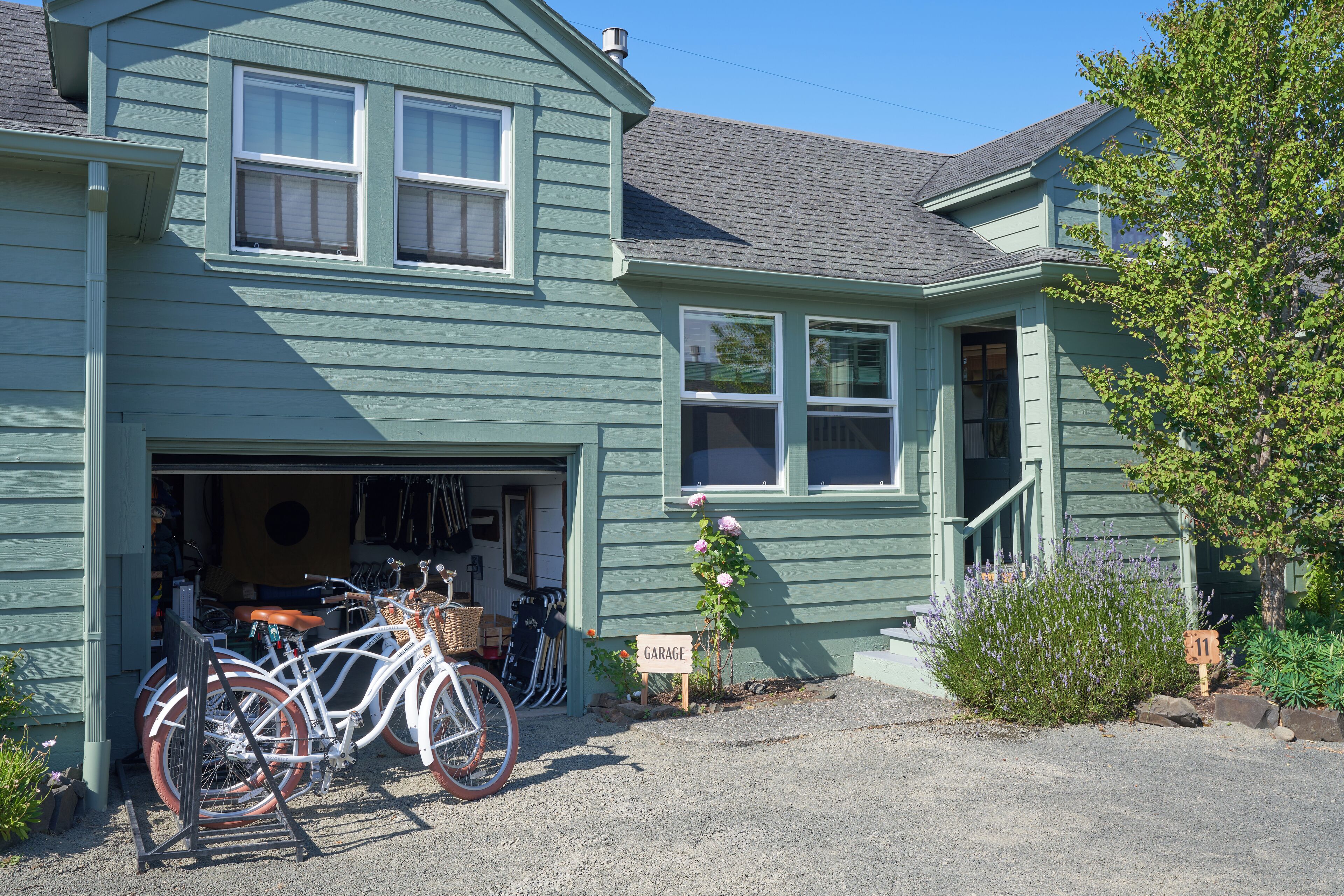 A two-story house with a garage, a bicycle, and a flower bed.