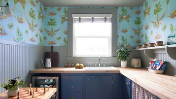 A kitchen with a wooden countertop, a sink, and a window with blinds. There is a chessboard on the counter and a plant in a pot.