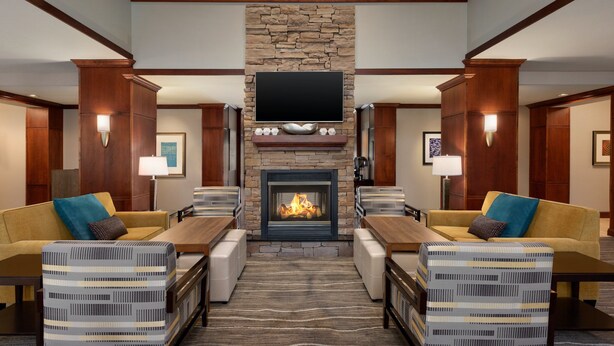 A spacious lobby with a stone fireplace, comfortable seating, and a flat-screen TV mounted above the fireplace.