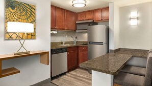 A modern kitchen with wooden cabinets, stainless steel appliances, and a built-in seating area.