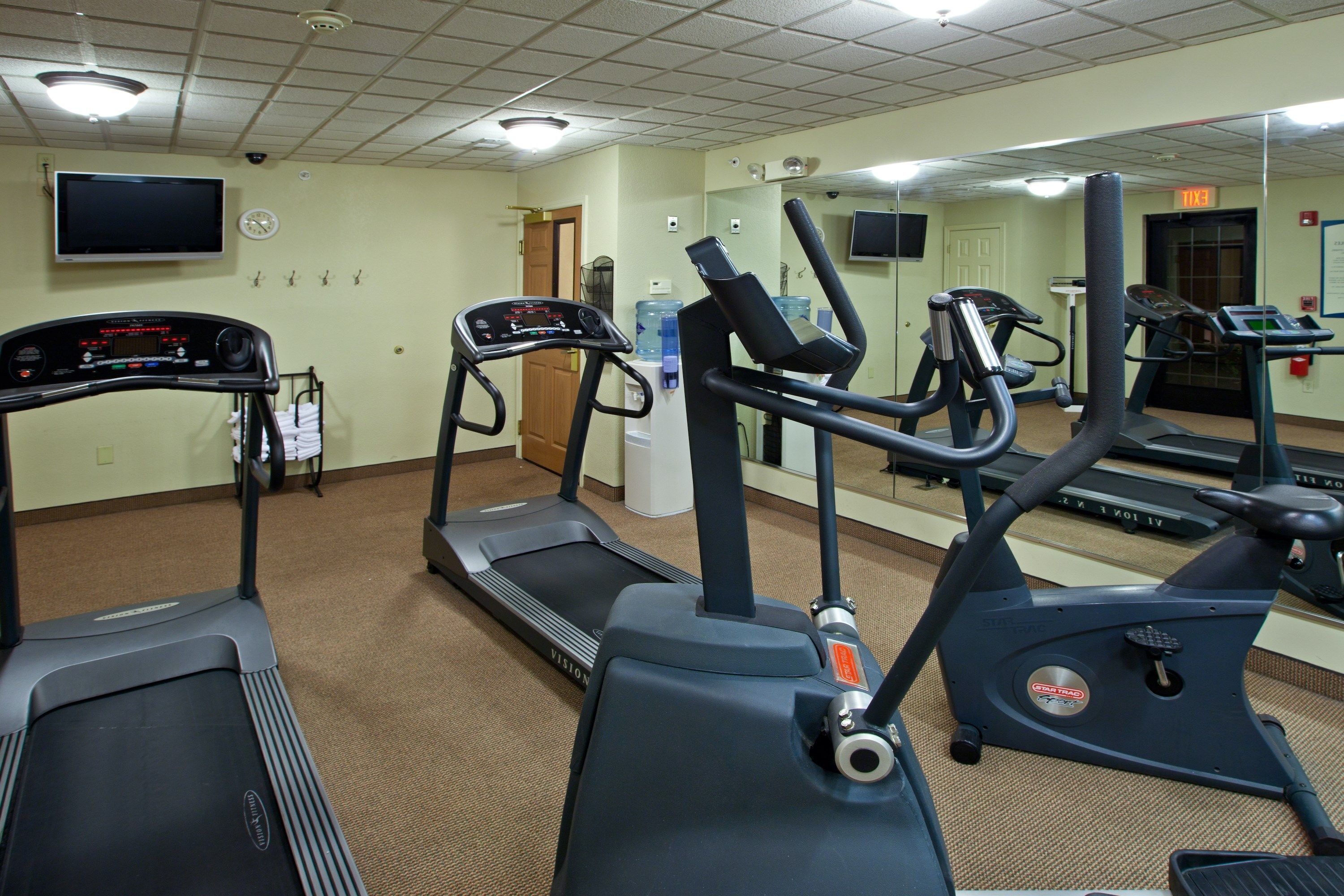 Un gimnasio con cintas de correr, elípticas y un dispensador de agua.
