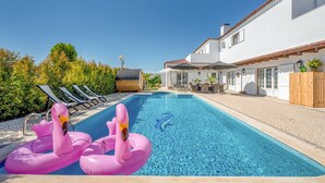 En pool med solstolar och två uppblåsbara flamingoflöten i rosa färg.