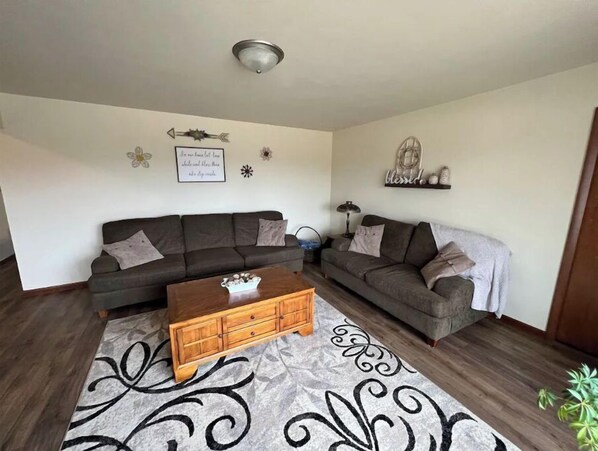 A living room with a dark brown sofa, a wooden coffee table, and a patterned rug. - Cheerful 3 bedroom home North side of Manitowoc (Manitowoc)