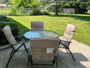 An outdoor patio with a round glass table and four cushioned chairs. - Cheerful 3 bedroom home North side of Manitowoc (Manitowoc)