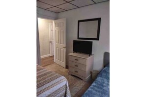 Cozy retreat with a bed, dresser, and TV.