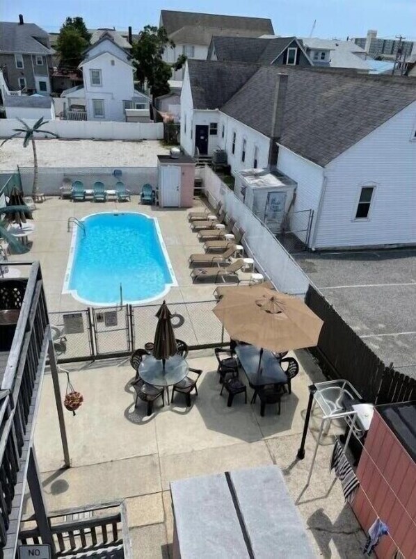 Relax by the pool surrounded by comfortable lounge chairs and a shaded table.