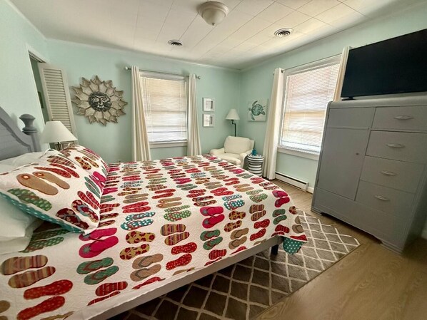 A bedroom with a bed, a dresser, a chair, and a window with blinds. - MoreBeachTime
Great Location
Family's & pets
Open Mid-week 8/19-22
& 8/24 > 9/5 (Kill Devil Hills)