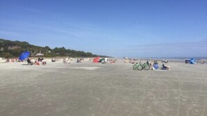 A beach with tents, bicycles, and people. - Labor Day Week (9/3-9/10) Ocean Resort Condo (Hilton Head Island)