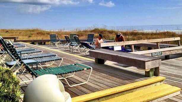 A wooden deck with lounge chairs and a wooden bench. - Labor Day Week (9/3-9/10) Ocean Resort Condo (Hilton Head Island)