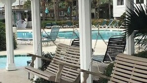 A poolside area with wooden loungers and a pool. - Labor Day Week (9/3-9/10) Ocean Resort Condo (Hilton Head Island)