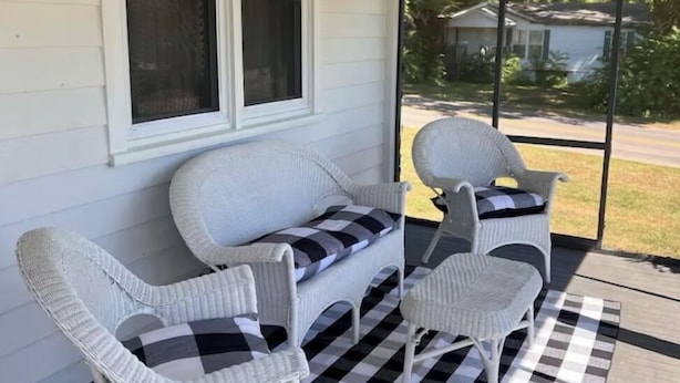 A covered porch with a checkered rug, two wicker chairs, and a sofa with a striped cushion. - The Jacks Fork Town House in Eminence (Eminence)