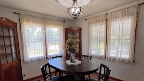 A dining room with a round table, six chairs, a vase with flowers, and a ceiling light fixture. - The Jacks Fork Town House in Eminence (Eminence)