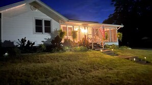 A two-story house with a front porch, a flag, and a well-lit entrance. - The Jacks Fork Town House in Eminence (Eminence)