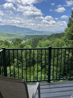 A deck with a view of a forested mountain range.