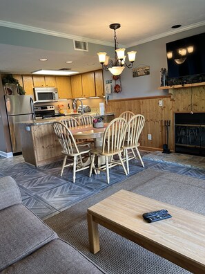 A modern kitchen with wooden cabinets, a microwave, and a dining area with a wooden table and chairs.